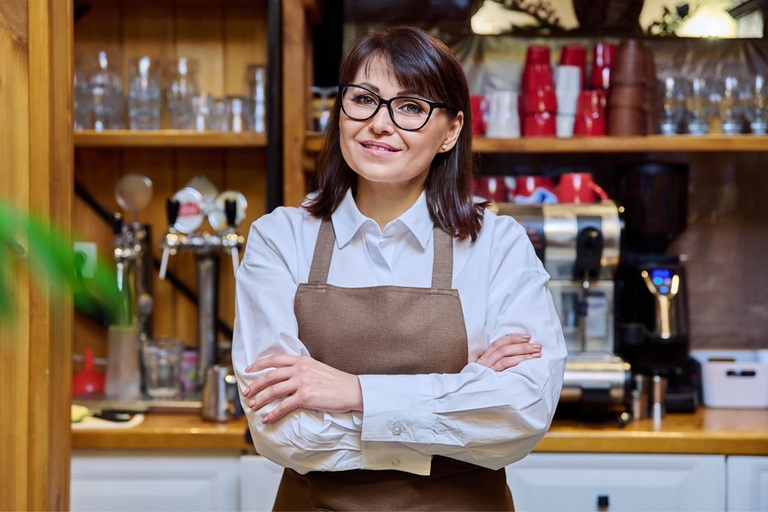 Frau mit Schürze hinter dem Tresen eines Cafés