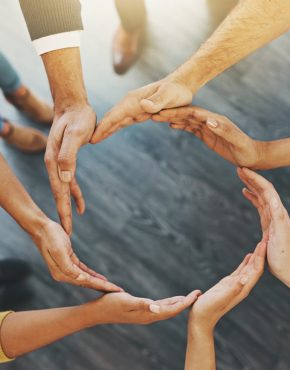 High angle shot of a group of unidentifiable businesspeople forming a circle with their hands.